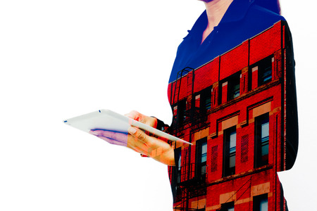 Silhouette of businesswoman working by tablet with apartment building and white background. Double exposure.の写真素材