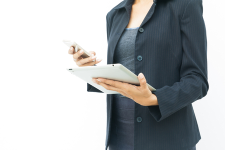 Business woman in dark suit using her tablet and mobile phone on white background with copy spaceの写真素材