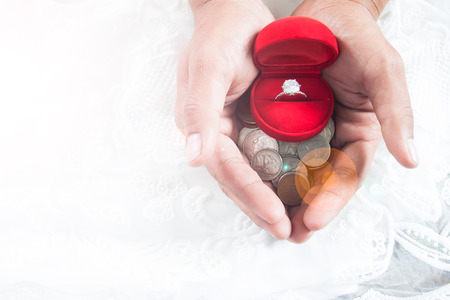 Saving money concept, love, couple, relationship - close up of man giving diamond ring with money coin in handの写真素材