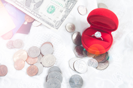 Saving money concept, love, couple, relationship - close up of diamond ring in red box with money coin, dollars and ATM cardの写真素材