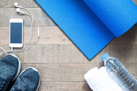 Flat lay of mobile phone with earphone and sport equipment on wood background. Sport accessories, Sport equipment, top viewの写真素材