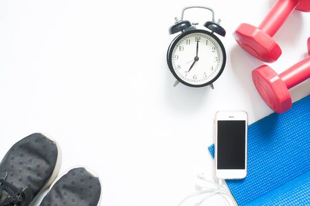 Flat lay of smartphone with sport yoga equipments and clock on white backgroundの写真素材