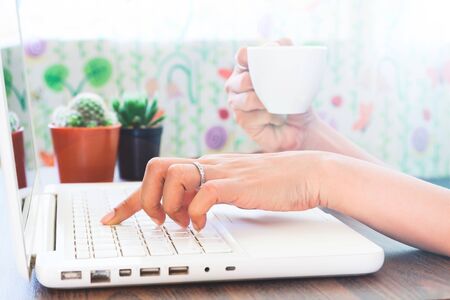 Woman using laptop and drinking coffee at home, Work at home concept