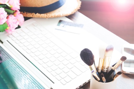 Beauty and online shopping concept with make-up brushes and computer laptopの写真素材