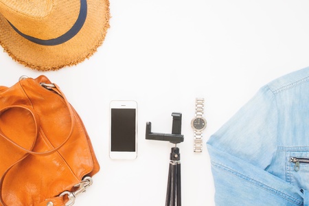Overhead view of mobile device and woman's accessories on white background, Lifestyle concept