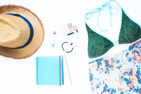 Flat lay of Beach and Summer items with cosmetics and blue color notebook on white background