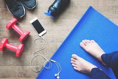 Selfie of feet yoga woman, smartphone, sport equipments and sport shoes on wood floorの写真素材
