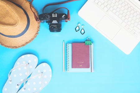 White laptop computer with woman accessories, camera and passport on blue color background, Summer travel conceptの写真素材