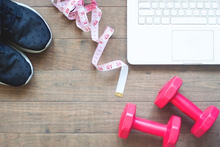 Creative flat lay of sport equipments and measuring-tape with laptop on wooden floor, Diet and Fitness conceptの写真素材