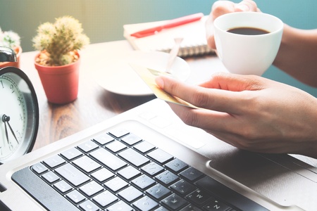 Happy woman drinking hot coffee and holding credit card, Online shopping concept