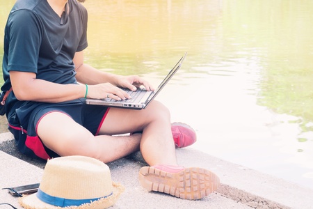 Asian man in casual clothing using laptop in public park, Lifestyle and Business conceptの写真素材