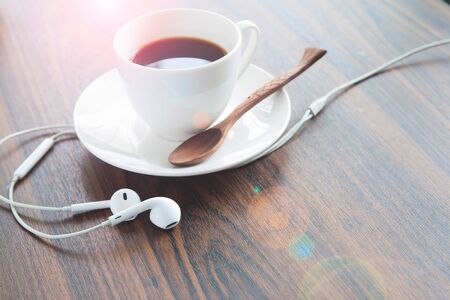 Earphones and coffee cup on wooden table, Lifestyle conceptの写真素材