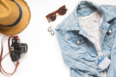 Creative flat lay of Travel items with camera and woman jacket jeans on white background