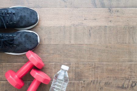 Creative flat lay of Healthy concept, woman Sport shoes, red color dumbbells and bottle of water on wood background with copy spaceの写真素材