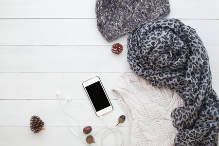 Flat lay of smart phone and woman clothing for winter on white wooden background,, Shopping and lifestyle conceptの写真素材
