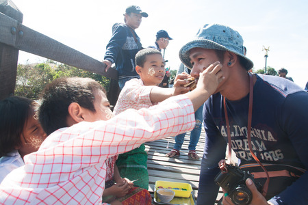 KANCHANABURI, THAILAND - JANUARY 1, 2018 : Lovely activity in Sangklaburi is local children make tanaka striped on tourist faces, Uttamanusorn Bridge, Landmark of Sangklaburi, Kanchanaburi, Thailandのeditorial素材