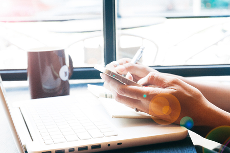 Close up of woman's hands using mobile phone and laptop, Online marketing or shopping conceptの写真素材