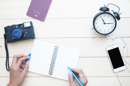 Woman's hand on diary notebook with camera, passport and mobile phone, Directly above travel concept の写真素材