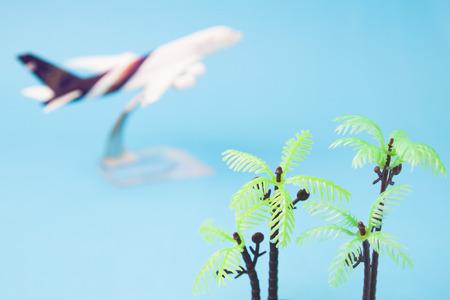 Plastic coconut palm tree with airplane model in background, Summer travel conceptの写真素材
