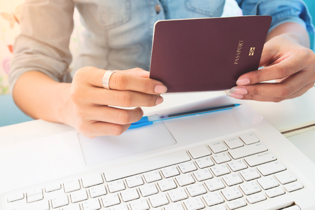 Close up image of woman's hands holding passport book on work space deskの写真素材