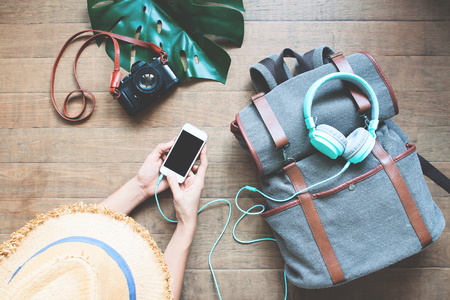 Top view tourist woman using smartphone with headphones on backpack, Holiday travel conceptの写真素材