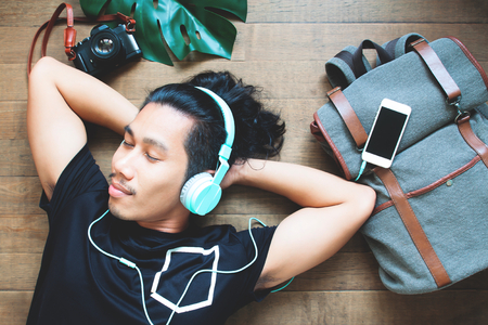 Happiness asian man listening to music laying down on the floor, Travel and vacation conceptの写真素材