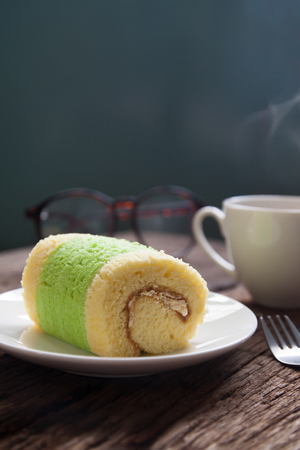 Close up roll cake with hot drink on wooden table, Rustic style conceptの写真素材