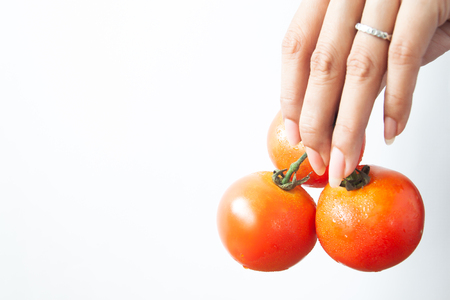 Beautiful woman hand with tomatoes on white background, Healthy and Beauty conceptの写真素材