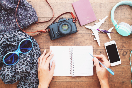 Top view woman's hands with blank notebook diary, smartphone, camera and passport. Travel lifestyle conceptの写真素材