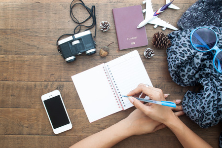 Preparation for travel, mobile phone, binoculars, passport and blank notebook with woman's hands, Flat layの写真素材