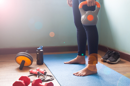 Woman exercise workout at home, fitness equipments and protein shake bottle on floorの写真素材