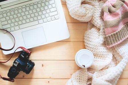 Creative flat lay of traveler's item, laptop computer, camera, Knitting sweater and takeaway coffee on wooden table, Travel and lifestyle conceptの写真素材