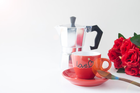Close up red coffee cup on white background with red rose and coffee potの写真素材