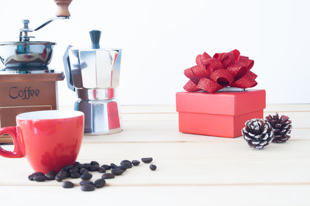 Red gift box with coffee pot, coffee grinder, red cup and roasted coffee beans on wooden table, Selective focusの写真素材