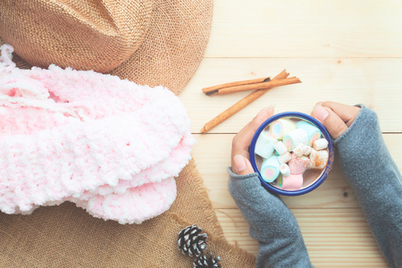 Creative flat lay of woman hands holding a cup hot chocolate with marshmallows topping, Vintage style filterの写真素材