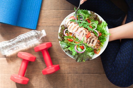 Healthy and fitness food. Chicken salad dish with fitness equipmentsの写真素材