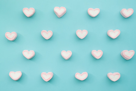 Flat lay top view tasty appetising concept, minimal pink heart shape marshmallow pattern on blue pastel background and copy space - Imageの写真素材