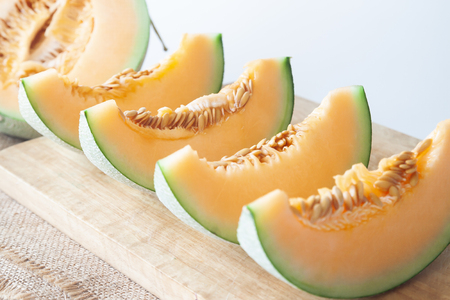 Fresh melons sliced on wooden cutting board. Healthy fruit. Selective focusの写真素材