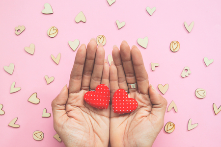 Creative flat lay of woman's hands with two hearts on pastel background. Love and Valentine's Day conceptの写真素材