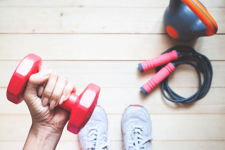 Overhead view of fitness girl holding red dumbbell with fitness equipments on wooden floor. Healthy and Diet conceptの写真素材