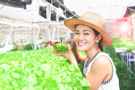 Young beautiful healthy woman holding salad bowl in organic vegetables farmの写真素材