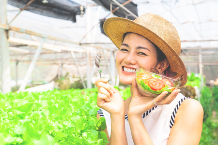 Beautiful woman holding salad bowl in organic farm. Healthy lifestyleの写真素材