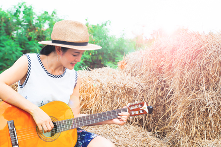 Asian woman playing guitar sitting on straw. Happy womanの写真素材