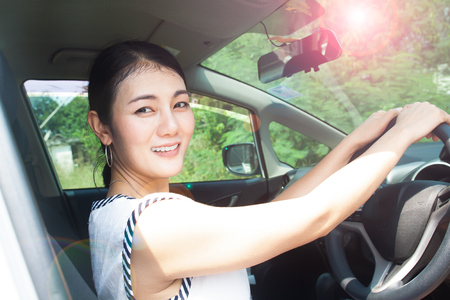 Asian woman driving car, sunny day. UV protection or skin care conceptの写真素材