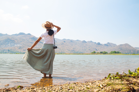Happy asian woman in casual style clothing standing in the river with mountain view on backgroundの写真素材