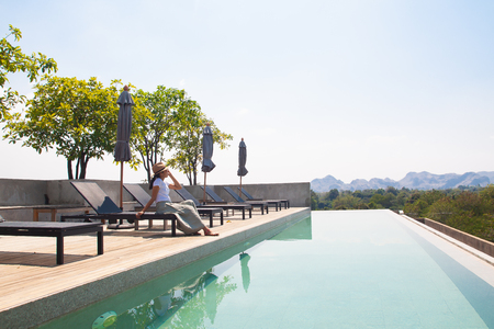 Asian woman relaxing at swimming pool on the roof topの写真素材