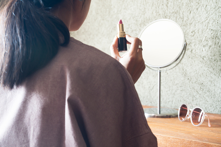 Asian woman holding lipstick preparing makeup to go out. Beauty and lifestyle conceptの写真素材