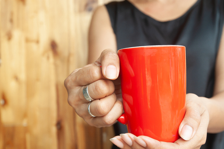 Woman hands holding red cup of coffee. Close upの写真素材