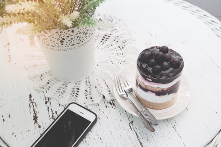 Blueberries short cake on vintage style table with mobile phone. Lifestyle conceptの写真素材