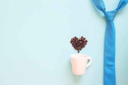 Happy Father's Day concept with blue colour necktie and coffee cup with coffee beans heart shape on pastel backgroundの写真素材
